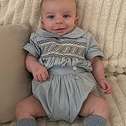 Tommy joined the competition — help win amazing prizes! baby, infant, smile, blue_outfit, white_shoes, blue_socks, blanket, pillow, couch, texture, indoor, cute, child, young, portrait, relaxing, soft_lighting, comfortable, happy, small