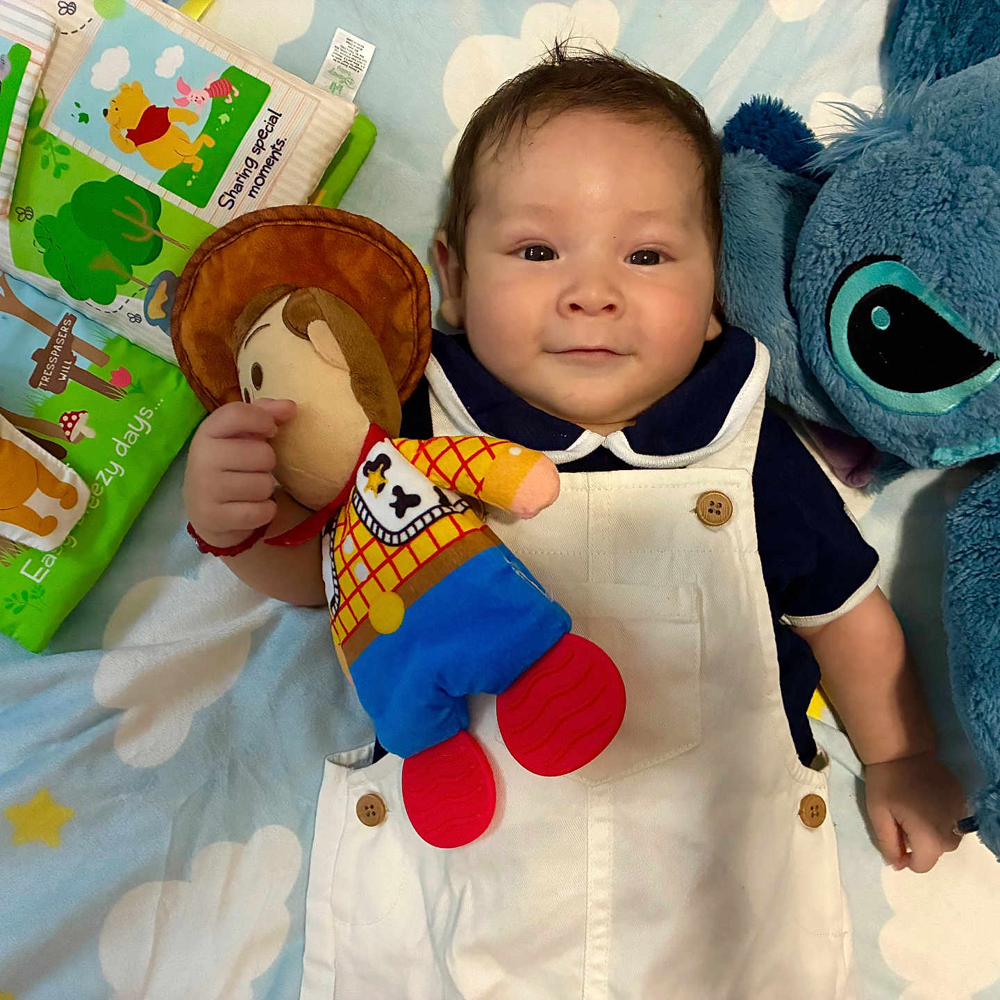 Aciel joined the competition — help win amazing prizes! baby, toy_story, woody_doll, stuffed_toy, plush, winnie_the_pooh, book, blanket, child, smiling, indoors, cute, blue, white_clothing, soft_toys, person, lying_down, colorful, happy, portrait