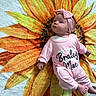 Braley is registered to the contest to win money with this photo: baby, infant, child, portrait, pink_outfit, headband, sunflower, blanket, lying_down, indoor, closeup, face, eyes_open, hands, feet, personalized_clothing, colorful, cozy, cute, photography
