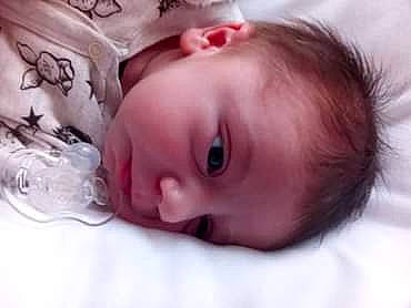 Tiago participe au concours pour gagner de l'argent avec cette photo : baby, baby_toddler_clothing, bedtime, cheek, child, close_up, comfort, ear, eyebrow, eyelash, happy, headgear, iris, linens, lip, mouth, nose, person, room, skin