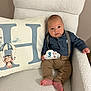 Henri a rejoint le concours — aidez-le/la à gagner de superbes lots ! baby, infant, milestone_card, 3_months, denim_shirt, suspenders, brown_pants, barefoot, white_chair, fluffy_texture, decorative_pillow, letter_h, parachuting_bear, cute, portrait, indoors, smiling, child, relaxed, cozy