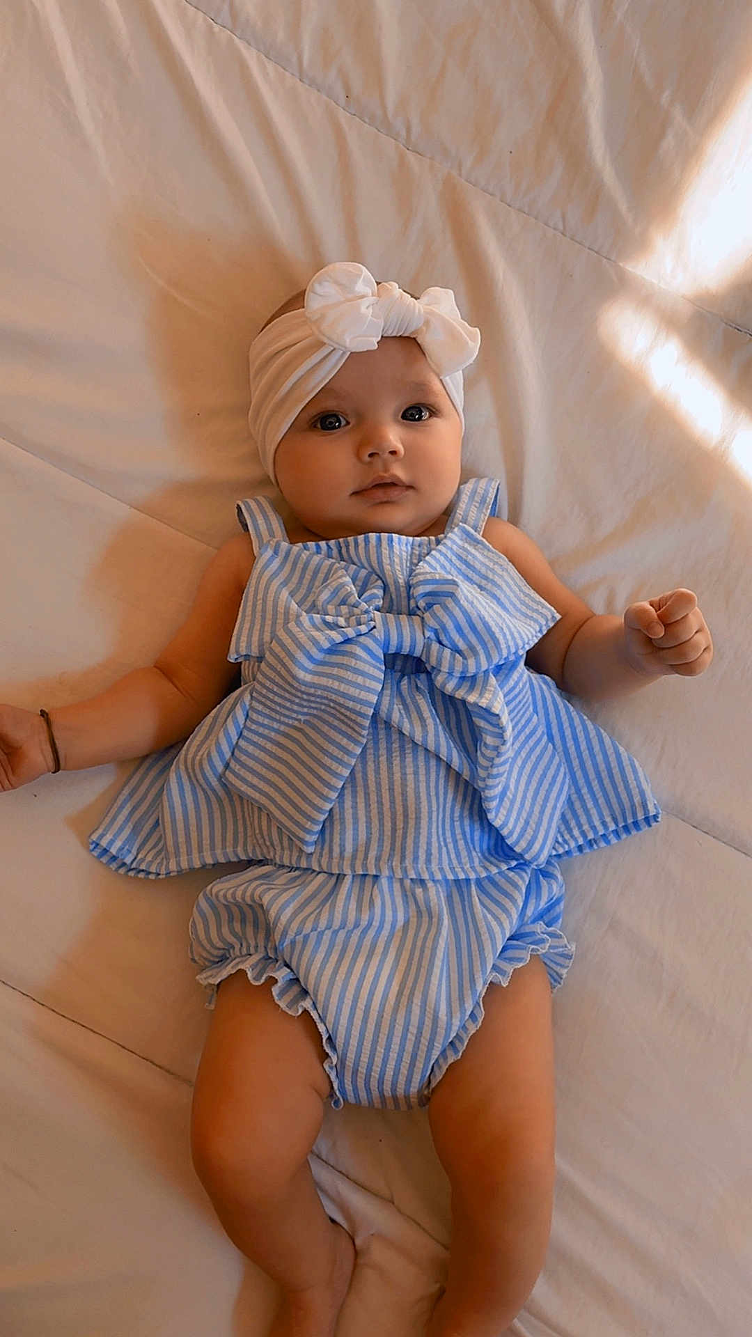 Alba a rejoint le concours — aidez-le/la à gagner de superbes lots ! arm, baby, baby_clothes, blue, bow, calm, child, cute, eyes, face, headband, indoors, infant, legs, lying_down, portrait, skin, soft_surface, striped_clothing, white