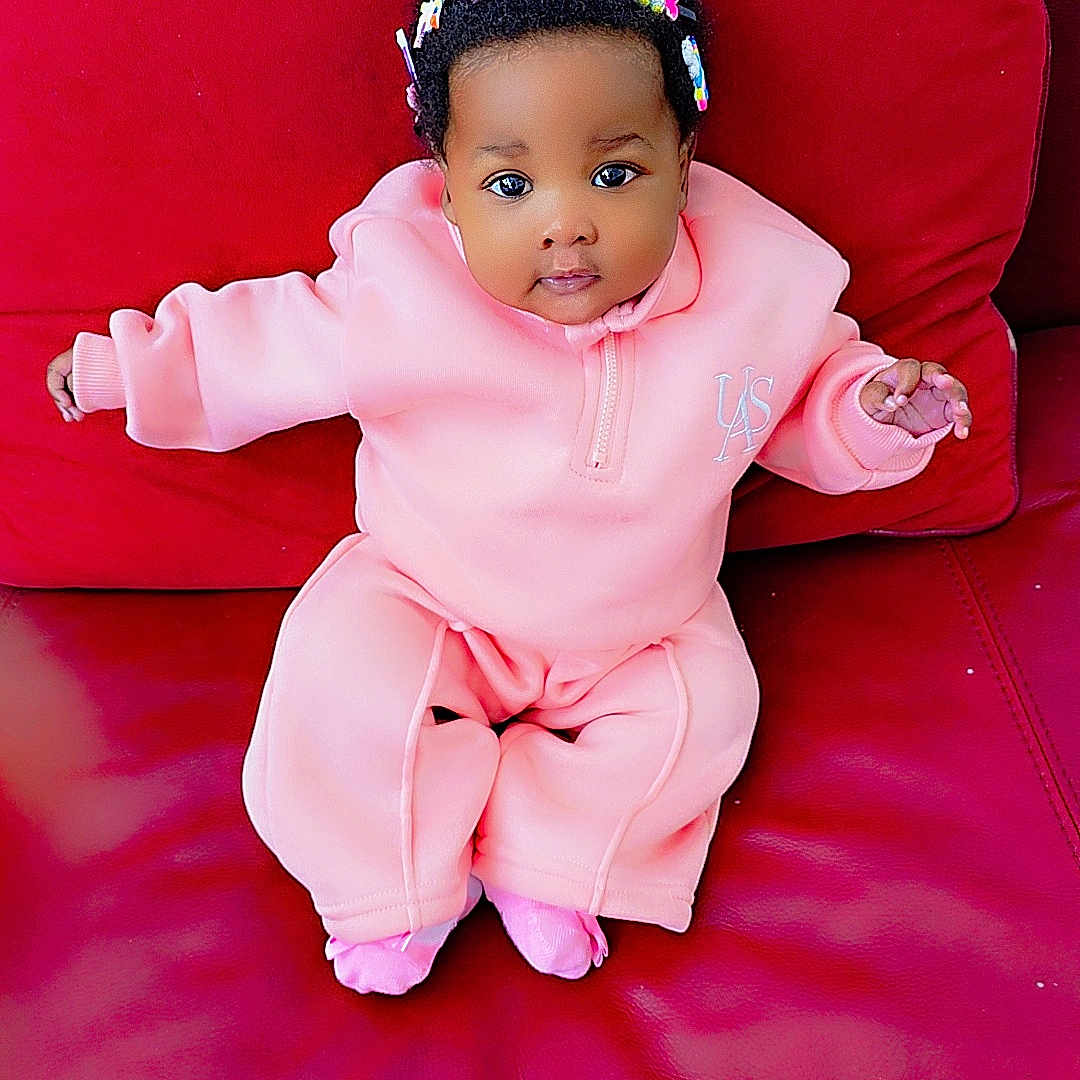 Ilerioluwa is registered to the contest to win money with this photo: adorable, baby, bright_colors, child, comfortable, cozy, cute, headband, indoors, infant, leather, looking_at_camera, pink_clothing, portrait, rainbow, red_couch, sitting, small_hands, unicorn, young