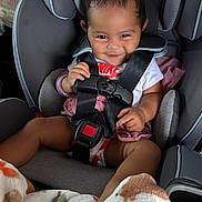 Melody is registered to the contest to win money with this photo: baby, child, car_seat, smile, happy, clothing, nike, blanket, seatbelt, infant, indoors, cute, person, sitting, safety, toddler, playful, hair, hand, face