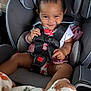 baby, child, car_seat, smile, happy, clothing, nike, blanket, seatbelt, infant, indoors, cute, person, sitting, safety, toddler, playful, hair, hand, face