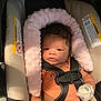 baby, infant, car_seat, seatbelt, mittens, pink_cushion, clothing, face, person, child, indoor, safety, resting, curly_hair, diaper, black_hair, cute, newborn, baby_girl, soft_texture
