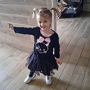 Angelina a rejoint le concours — aidez-le/la à gagner de superbes lots ! black_dress, blanket, casual_clothing, child, couch, cute, dog_in_background, girl, happy, indoor, living_room, pigtails, pink_bow, playful, portrait, pose, smile, sneakers, tiles, wood_floor