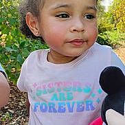 Amaya is registered to the contest to win money with this photo: child, girl, curly_hair, outdoor, bench, tshirt, plush_toy, mickey_mouse, greenery, sunlight, rosy_cheeks, portrait, casual_clothing, smiling, earrings, nature, daylight, cute, sitting, playful