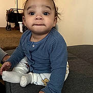 Elijah joined the competition — help win amazing prizes! baby, child, infant, blue_sweater, white_pants, teddy_bear_print, curly_hair, sitting, couch, indoor, carpet, face, eyes, hand, foot, expression, clothing, person, portrait, cute