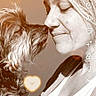 dog, woman, nose_to_nose, affection, sepia_tone, portrait, pet, face, love, smile, fur, close_up, social_media_interface, app_buttons, human, animal, candid, indoor, warm_lighting, interaction