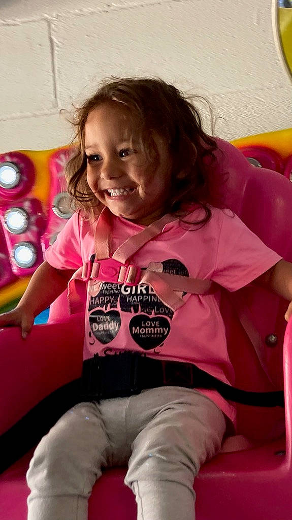 Brooklyn is registered to the contest to win money with this photo: abdomen, child, comfort, fun, happy, human_leg, joy, knee, lap, leisure, magenta, person, pink, play, room, sitting, skin, sleeve, smile, t_shirt