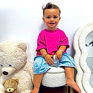 Milann a rejoint le concours — aidez-le/la à gagner de superbes lots ! toddler, child, smiling, pink_shirt, denim_shorts, barefoot, stuffed_teddy_bear, plush_toy, white_wall, mirror, chair, carpet, indoor, cute, happy, portrait, sitting, toy, cozy, home_decor