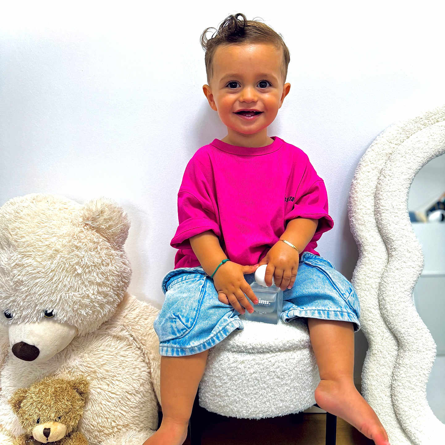 Milann a rejoint le concours — aidez-le/la à gagner de superbes lots ! barefoot, carpet, chair, child, cozy, cute, denim_shorts, happy, home_decor, indoor, mirror, pink_shirt, plush_toy, portrait, sitting, smiling, stuffed_teddy_bear, toddler, toy, white_wall