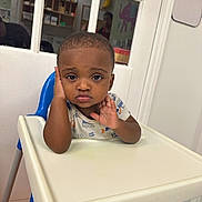 Denim joined the competition — help win amazing prizes! toddler, child, high_chair, indoor, contemplative, hand_on_face, short_hair, white_door, glass_panels, shelf, colorful_background, floor_mat, blue_chair, casual_clothing, person, portrait, young_child, expression, seated, baby