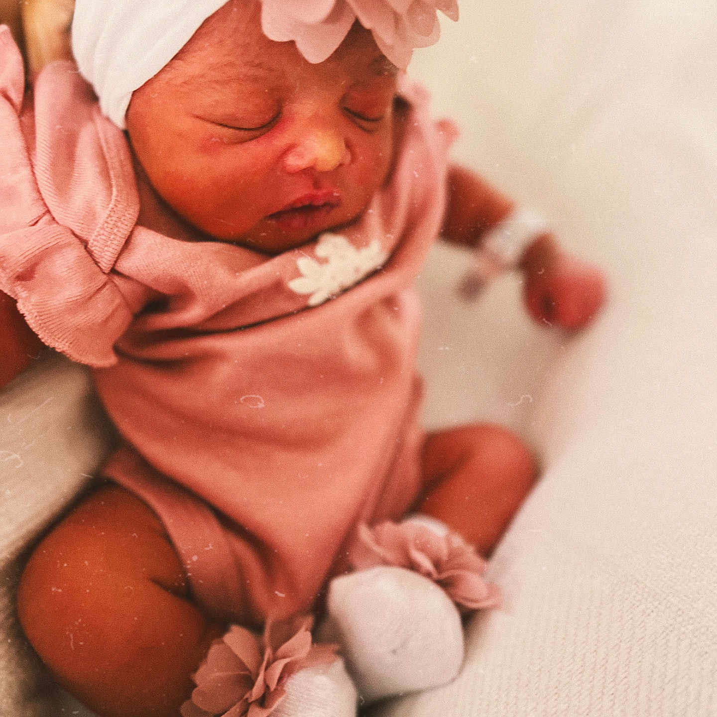 Xamira is registered to the contest to win money with this photo: adorable, baby, child, close_up, cozy, cute, flower_accessory, headband, indoor, infant, newborn, peaceful, pink_clothing, portrait, resting, sleeping, small_feet, soft_blanket, soft_lighting, white_socks