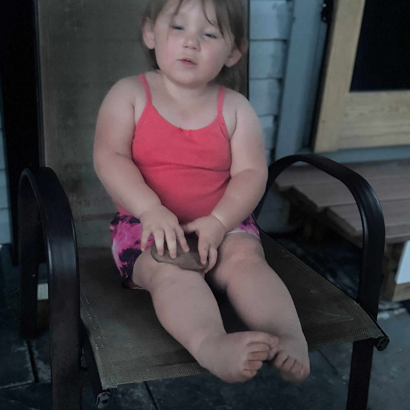 Leila is registered to the contest to win money with this photo: barefoot, casual, chair, child, daylight, expression, face, hands, legs, mesh_chair, object, outdoor, person, pink_top, porch, shorts, sitting, stone_floor, toddler, wooden_door