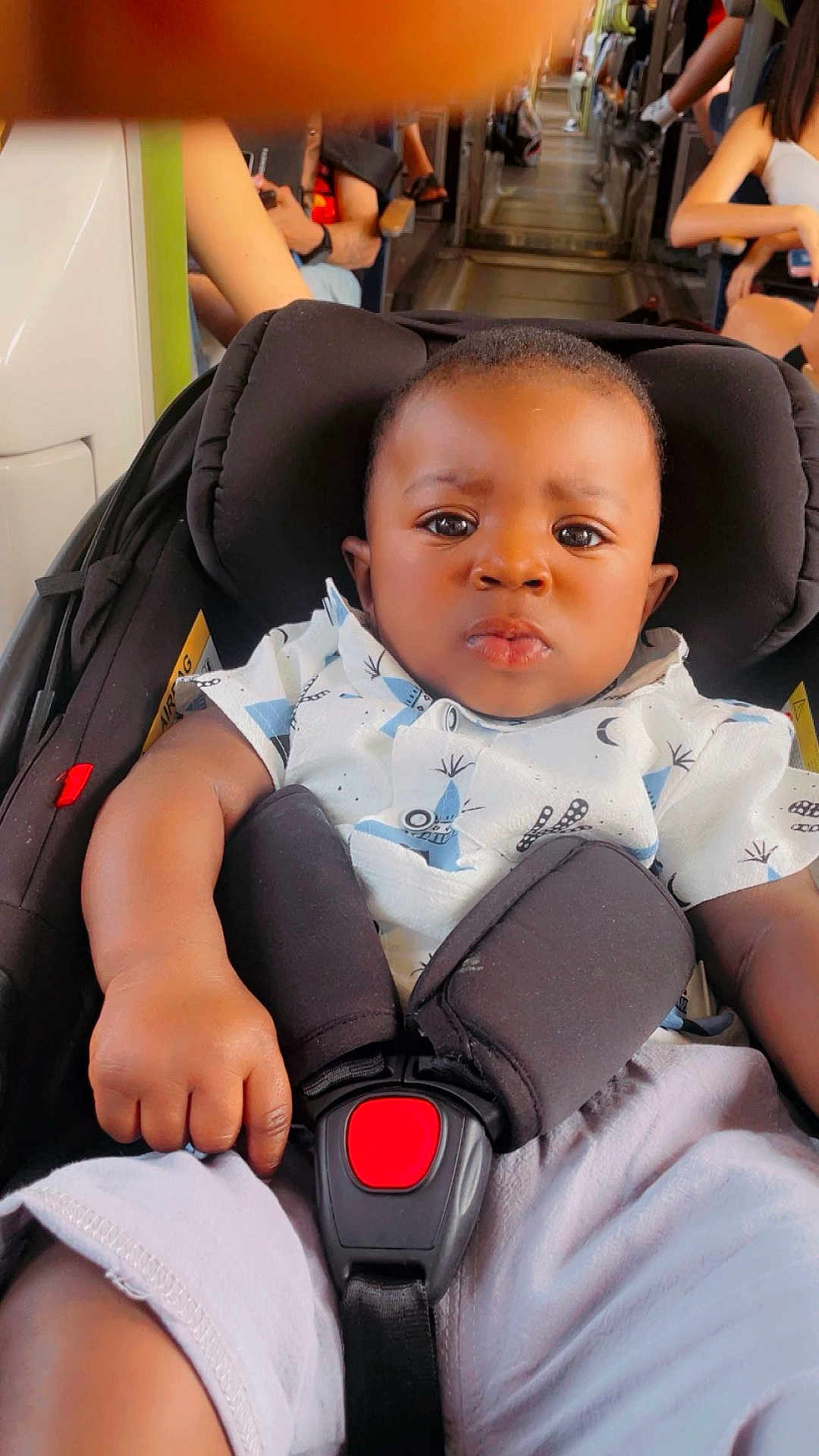 Liam a rejoint le concours — aidez-le/la à gagner de superbes lots ! baby, car_seat, child, infant, seatbelt, bus, public_transport, people, hand, clothing, expression, serious, person, indoor, sitting, shoulder, shorts, shirt, black_hair, skin