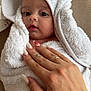 baby, towel, hooded_towel, hand, tattoo, manicure, nails, skin, face, eyes, mouth, blanket, white, cozy, infant, person, portrait, closeup, soft, couch