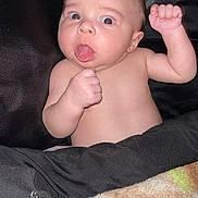 Omari is registered to the contest to win money with this photo: baby, bed, bodypart, clothing, couch, cushion, face, finger, furniture, hand, head, homedecor, mouth, newborn, pants, person, photography, portrait, quilt, tongue