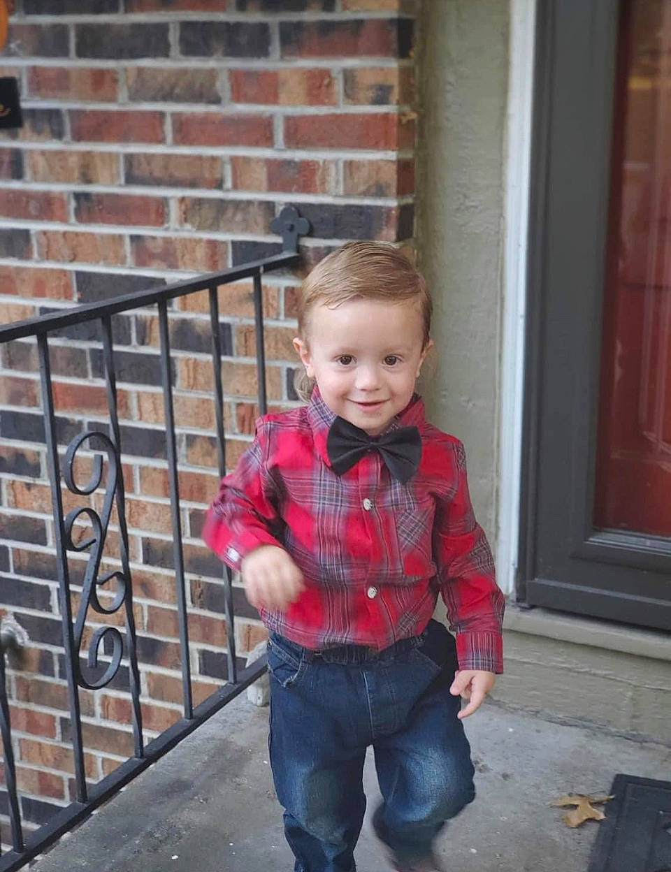 William is registered to the contest to win money with this photo: baby_toddler_clothing, brick, brickwork, clothing, cool, denim, door, dress_shirt, electric_blue, happy, jeans, joy, pattern, person, plaid, sleeve, smile, standing, tartan, toddler