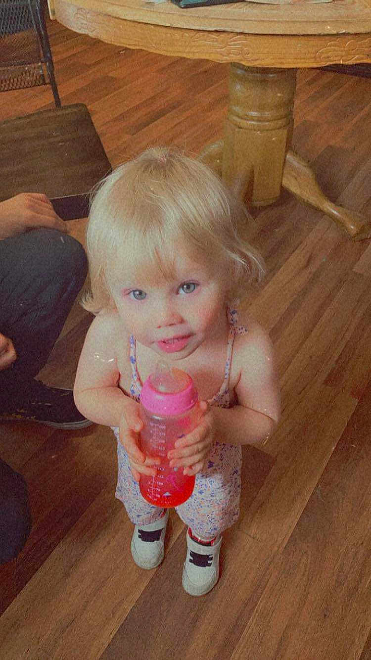 Juliet is registered to the contest to win money with this photo: adult, bottle, child, clothing, diningtable, face, female, footwear, furniture, girl, hardwood, head, indoors, interiordesign, person, photography, portrait, shoe, table, wood