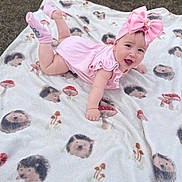 Erika is registered to the contest to win money with this photo: baby, child, pink_dress, headband, bow, blanket, hedgehog_pattern, mushroom_pattern, outdoor, grass, tummy_pose, smiling, cute, infant, happy, clothing, sock, portrait, playtime, soft_texture