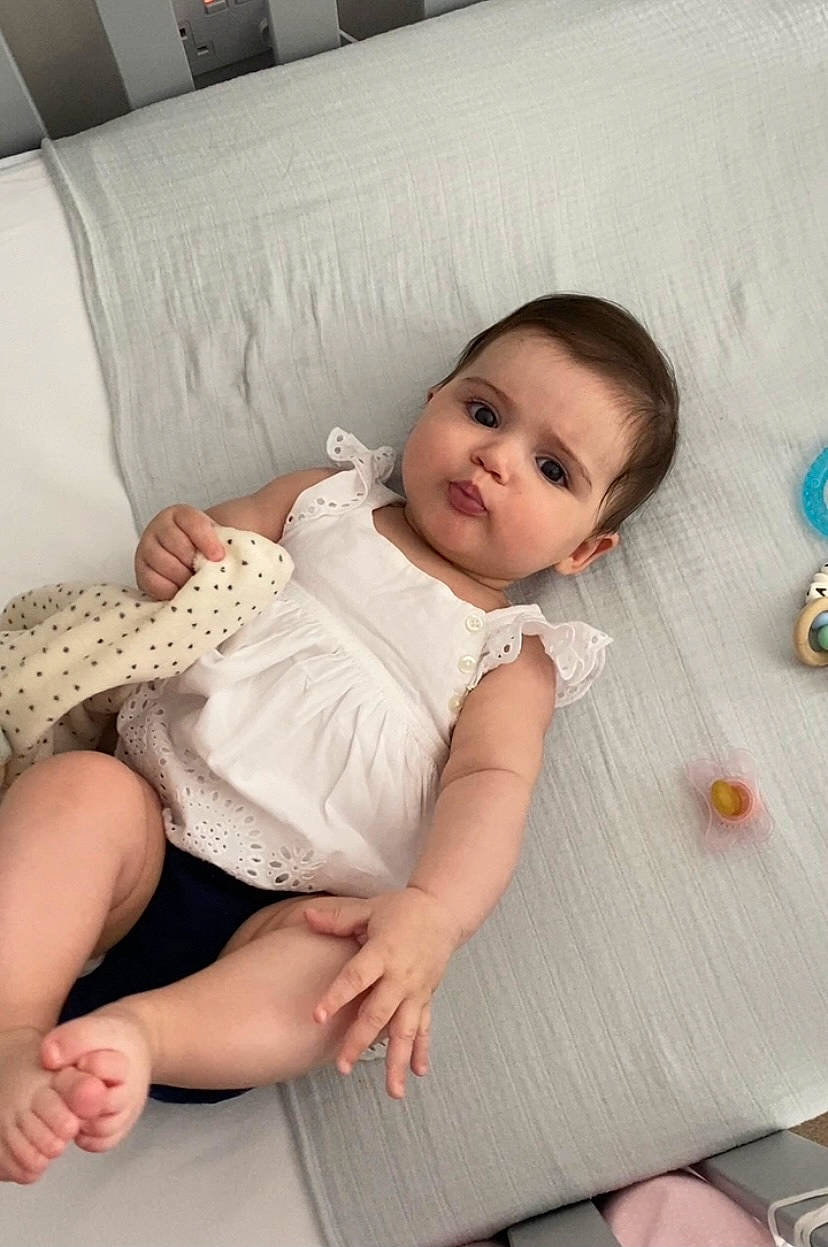 Anya is registered to the contest to win money with this photo: baby, baby_toddler_clothing, cheek, child, comfort, foot, hair, hairstyle, head, human_leg, knee, pattern, person, pink, skin, sleeve, textile, thigh, toddler, white