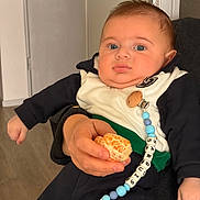 Sarguis a rejoint le concours — aidez-le/la à gagner de superbes lots ! baby, infant, child, bead_chain, pacifier_clip, mandarin, fruit, adult_hand, onesie, jacket, blue_eyes, chubby_cheeks, portrait, indoor, sitting, expression, skin, furniture, flooring, close_up