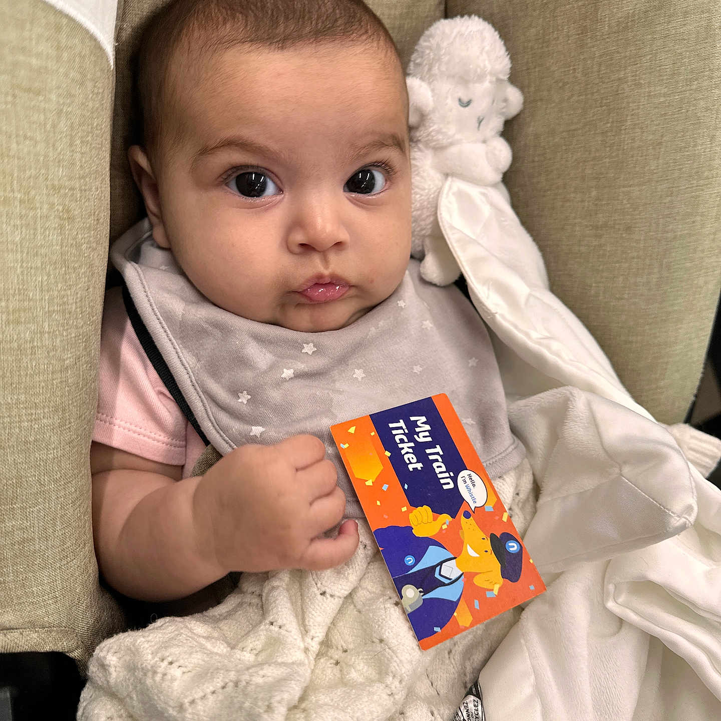 Anah is registered to the contest to win money with this photo: baby, blanket, card, child, clothing, comfort, cozy, cute, expression, eyes, face, hand, indoor, infant, person, plush_toy, portrait, seat, soft, ticket