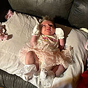 Gabriella is registered to the contest to win money with this photo: baby, infant, tutu, mittens, couch, pillow, white, pink, clothing, cute, lying_down, indoor, soft, fabric, child, newborn, person, small, cozy, home