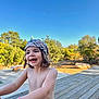 bare_chest, blue_sky, bracelet, carefree, child, daylight, happy, headscarf, joyful, nature, outdoor, person, playing, portrait, smiling, summer, sunlight, trees, wooden_deck, young