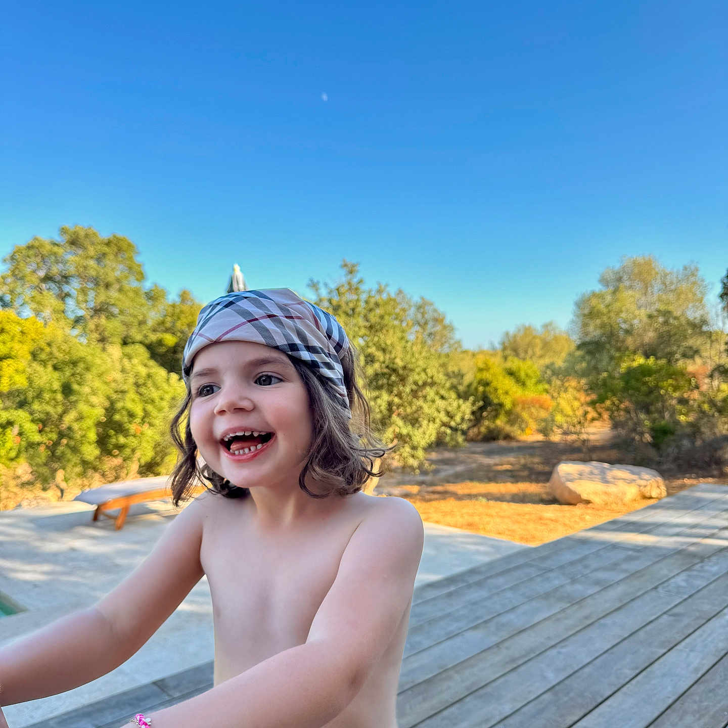 Clémence participe au concours pour gagner de l'argent avec cette photo : bare_chest, blue_sky, bracelet, carefree, child, daylight, happy, headscarf, joyful, nature, outdoor, person, playing, portrait, smiling, summer, sunlight, trees, wooden_deck, young
