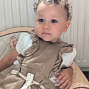 Capucine participe au concours pour gagner de l'argent avec cette photo : toddler, child, curly_hair, blue_eyes, bow, beige_dress, ruffles, chair, floral_pattern, indoor, portrait, cute, sitting, hand, young_child, light_skin, white_shirt, fabric, furniture, expression