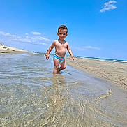 Raphaël participe au concours pour gagner de l'argent avec cette photo : child, beach, water, ocean, sky, sand, sunny, swim_diaper, toddler, outdoor, daytime, waves, shore, nature, summer, vacation, happy, playing, walking, coast