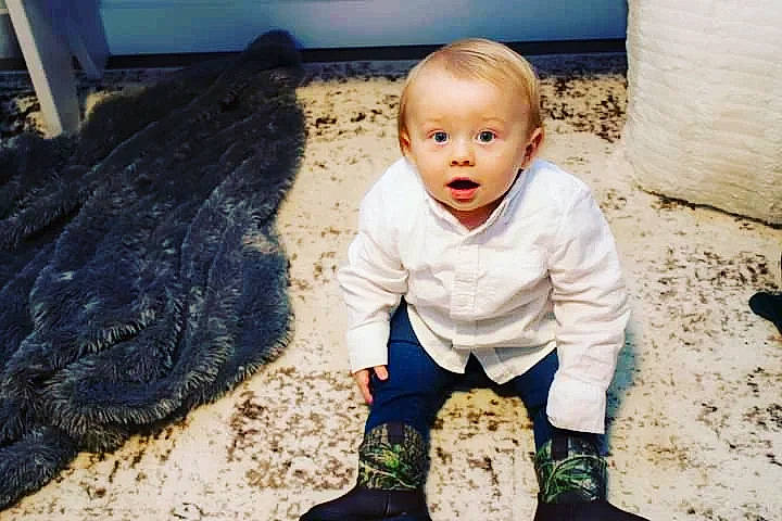 James is registered to the contest to win money with this photo: automotive_tire, baby, baby_toddler_clothing, child, facial_expression, flash_photography, flooring, fun, grass, happy, human, people_in_nature, person, play, rock, sand, sitting, soil, surprise, toddler