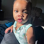 Niko joined the competition — help win amazing prizes! arm, baby, child, clothing, couch, curly_hair, expression, face, furniture, hand, home, indoor, living_room, person, portrait, skin, sleeveless_shirt, sunlight, toddler, tongue