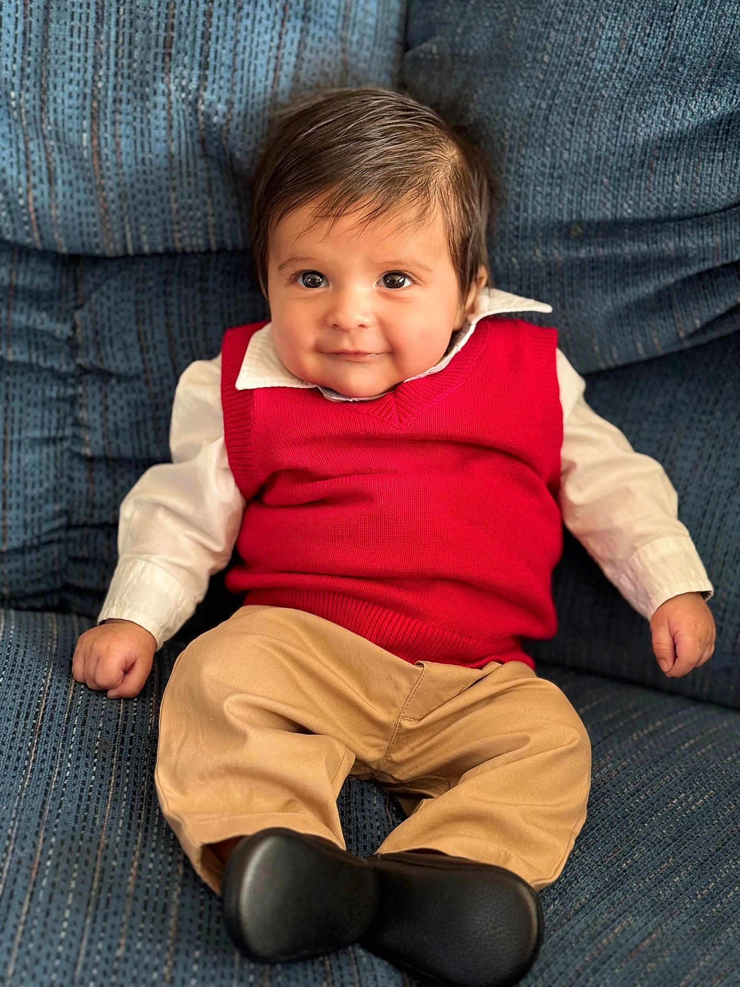 Liam joined the competition — help win amazing prizes! baby, infant, child, red_sweater, white_shirt, khaki_pants, black_shoes, blue_couch, upholstery, portrait, smile, dark_hair, big_eyes, sitting, indoors, cute, hands, feet, collar, fashion