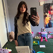 Brinley is registered to the contest to win money with this photo: person, mirror, selfie, jeans, long_hair, sweater, room, toys, mirror_selfie, smartphone, casual_clothing, carpet, makeup_brush, hairbrush, table, child_toys, poster, pink, green, reflection