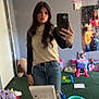 Brinley is registered to the contest to win money with this photo: person, mirror, selfie, jeans, long_hair, sweater, room, toys, mirror_selfie, smartphone, casual_clothing, carpet, makeup_brush, hairbrush, table, child_toys, poster, pink, green, reflection