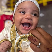 Mohamed participe au concours pour gagner de l'argent avec cette photo : baby, infant, smiling, happy, face, hand, henna, ring, clothing, embroidery, white, gold, closeup, portrait, cute, child, person, celebration, joy, cultural