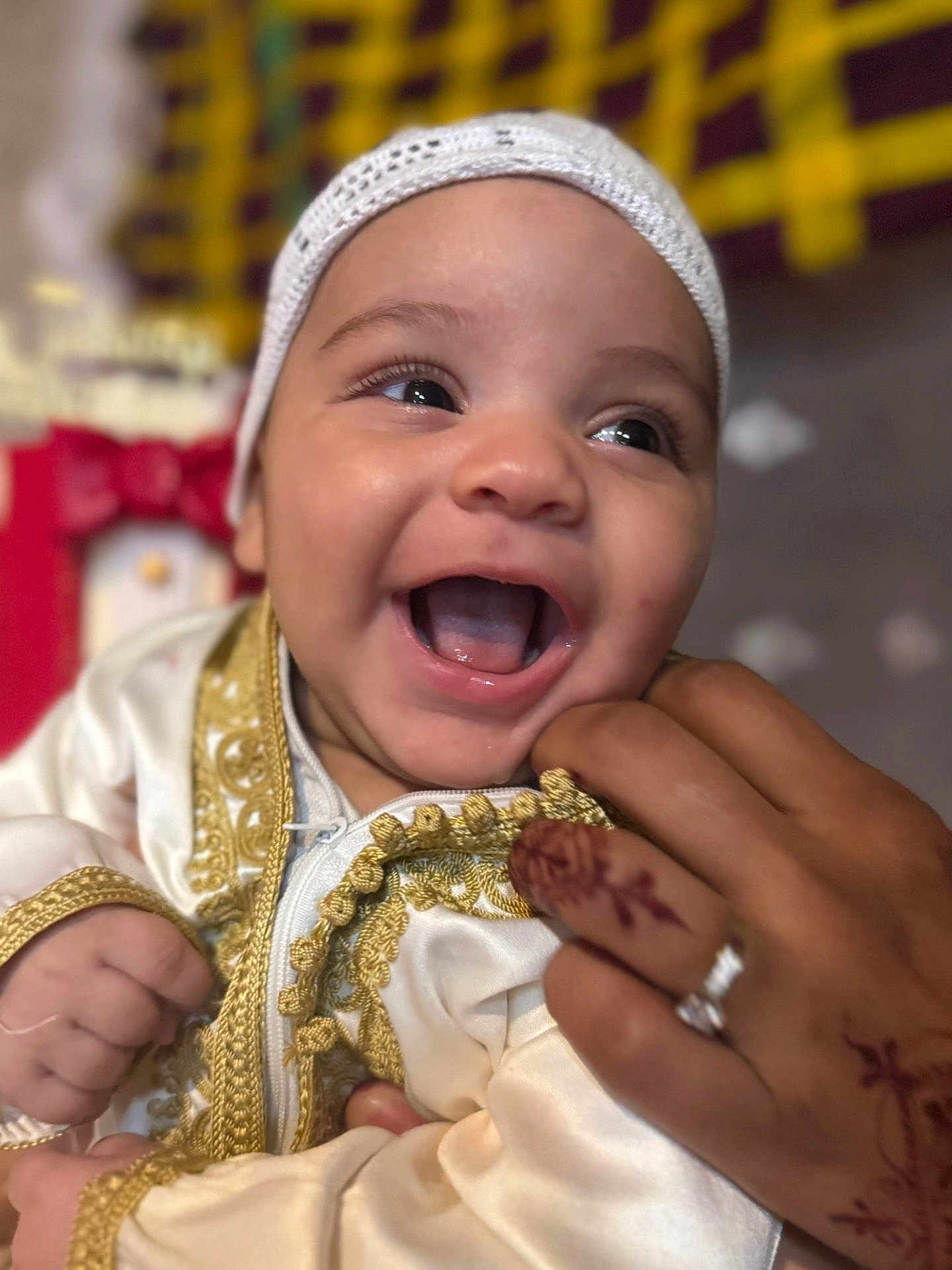 Mohamed participe au concours pour gagner de l'argent avec cette photo : baby, infant, smiling, happy, face, hand, henna, ring, clothing, embroidery, white, gold, closeup, portrait, cute, child, person, celebration, joy, cultural