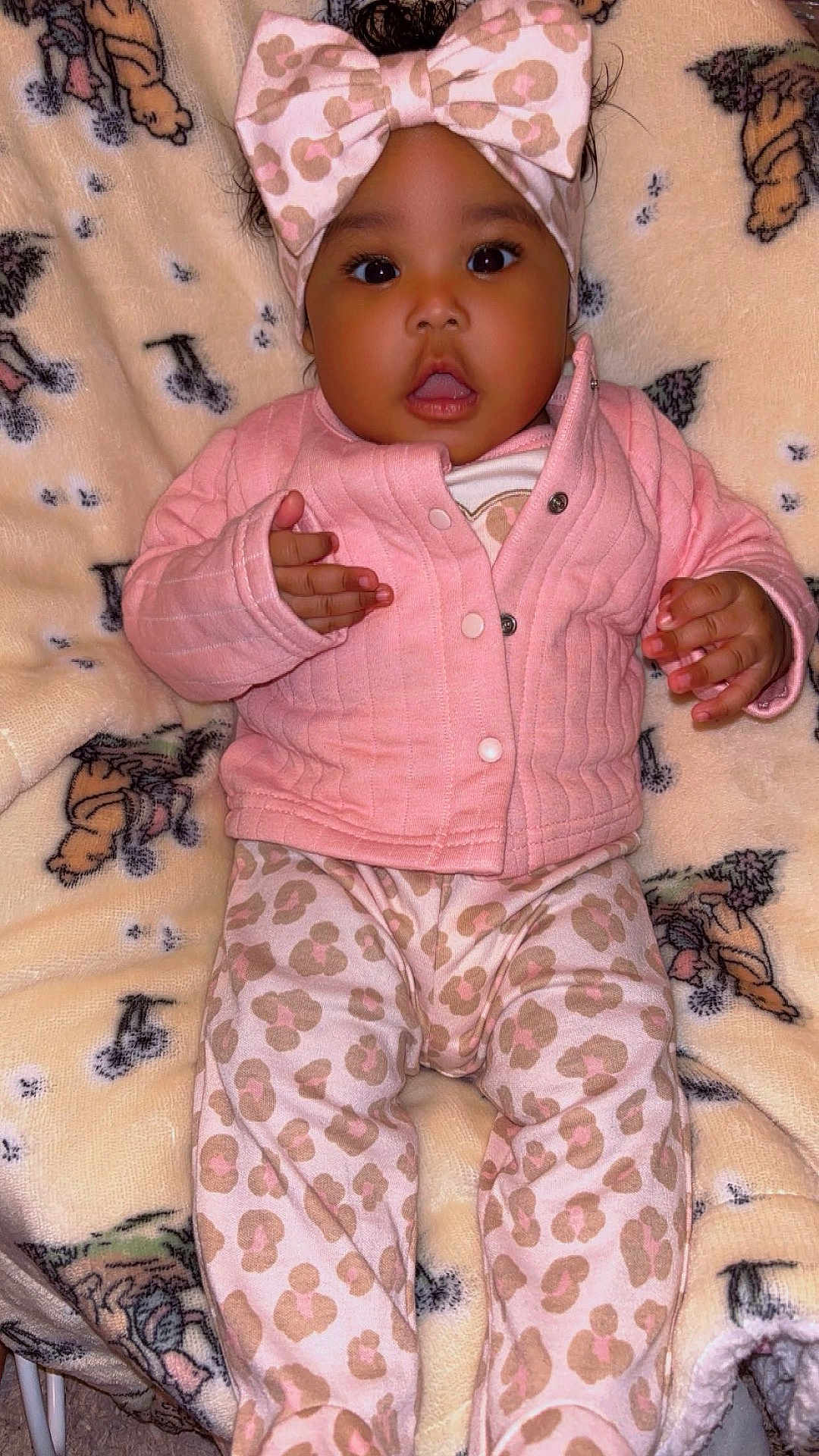 Blessynn is registered to the contest to win money with this photo: baby, child, pink_clothing, headband, leopard_print, blanket, indoor, cute, portrait, infant, jacket, pants, pattern, soft_texture, lying_down, hands, face, wide_eyes, expression, warm