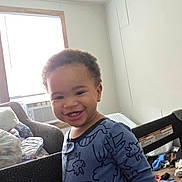 Jayden joined the competition — help win amazing prizes! toddler, child, smiling, indoor, onesie, dinosaur_pattern, baby, face, air_conditioner, chair, window, toys, floor, happy, home, person, clothing, portrait, furniture, playpen
