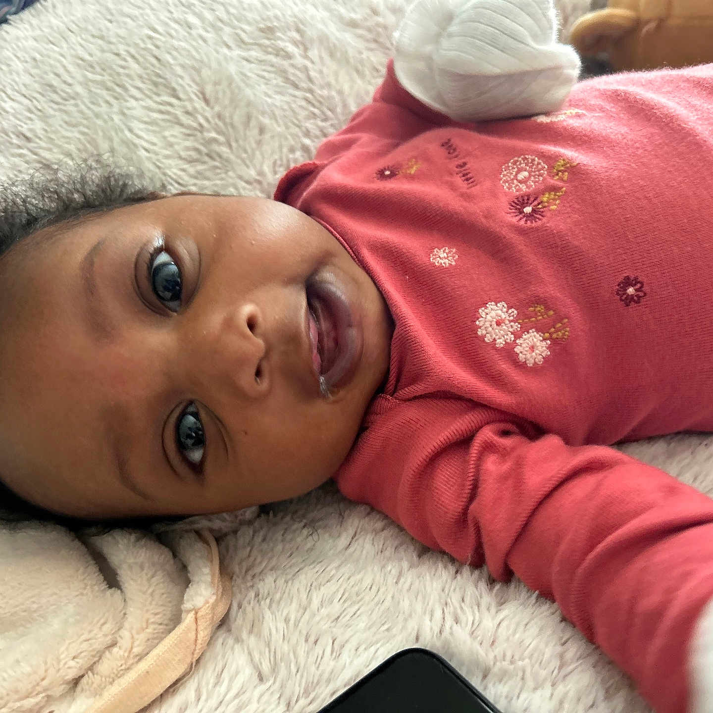 Cyanna joined the competition — help win amazing prizes! baby, infant, lying_down, red_onesie, fluffy_blanket, smiling, drool, cute, face, hand, soft_texture, close_up, indoors, child, young_child, cozy, warm_clothing, relaxed, happy, portrait