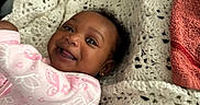 Cyanna is registered to the contest to win money with this photo: baby, blanket, butterfly_pattern, child, cozy, crochet, cute, earrings, eyes, face, happy, indoor, infant, lying_down, person, pink_clothing, portrait, smile, soft, texture