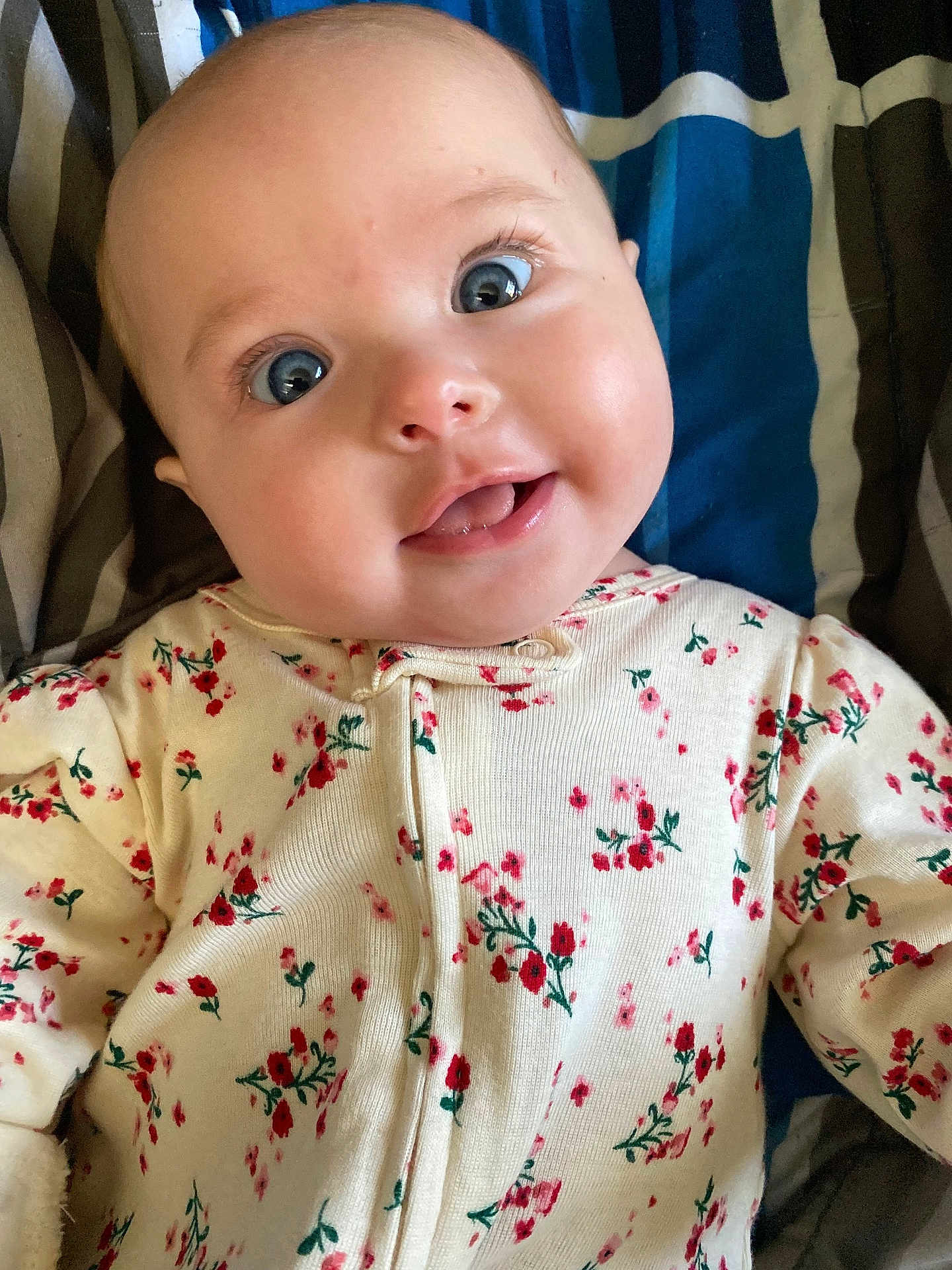 Kathryn joined the competition — help win amazing prizes! baby, infant, face, eyes, tongue, clothing, onesie, floral_pattern, blanket, striped, cute, portrait, child, smiling, happy, skin, young, person, indoors, closeup