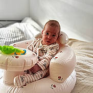 Michelle is registered to the contest to win money with this photo: baby, bed, blanket, child, cozy, cute, floral_pattern, home, indoor, infant, inflatable_chair, looking_at_camera, nursery, pajamas, person, seated, soft_lighting, striped_clothing, toy, young_child