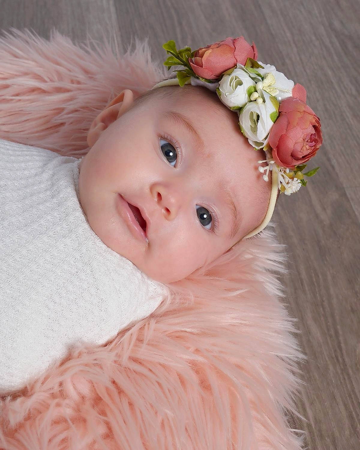 Megan is registered to the contest to win money with this photo: baby, baby_toddler_clothing, bridal_accessory, costume_hat, dress, embellishment, flash_photography, flower, happy, headband, headgear, headpiece, headwear, iris, natural_material, person, petal, pink, plant, rose