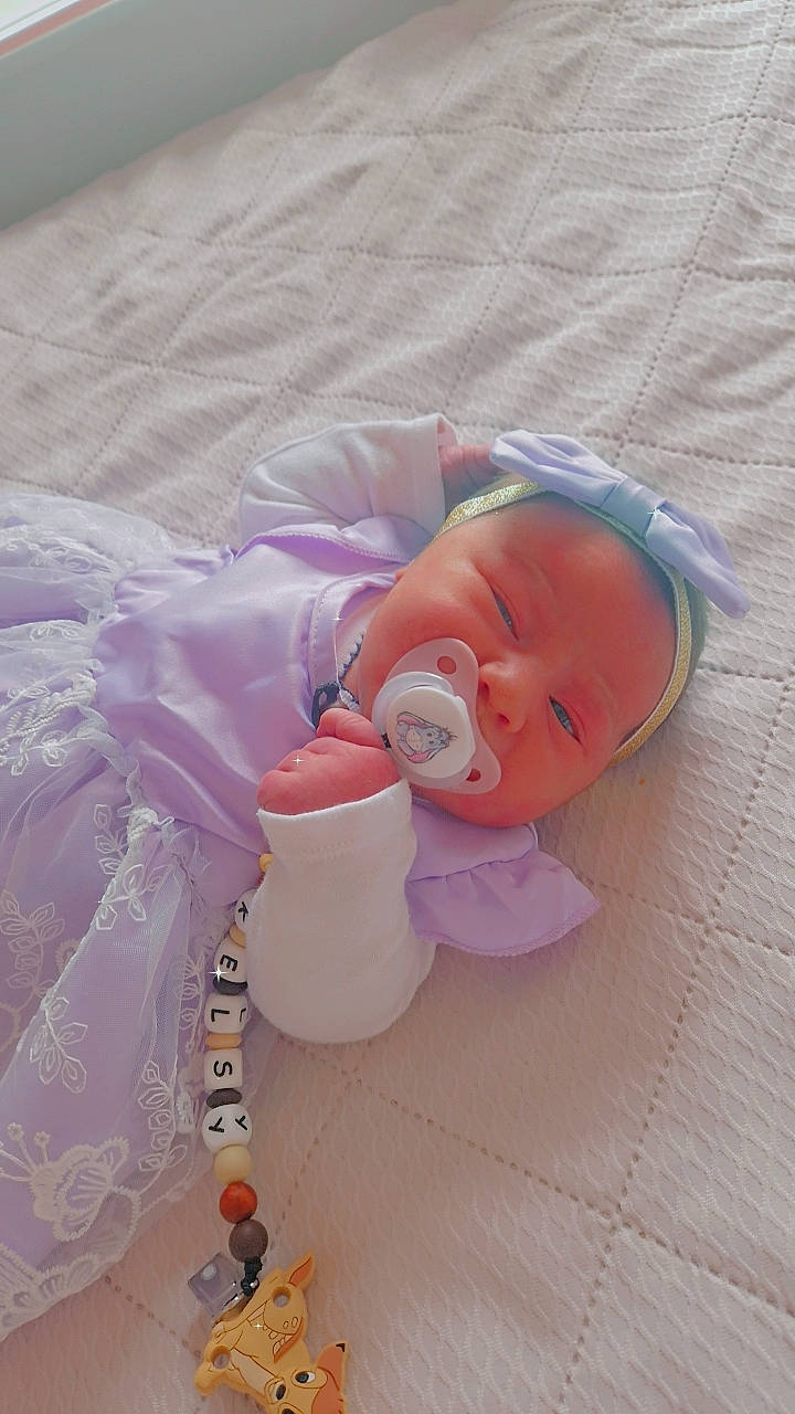 Kelsy a rejoint le concours — aidez-le/la à gagner de superbes lots ! baby, baby_products, baby_safety, baby_sleeping, baby_toddler_clothing, baby_toys, child, comfort, fashion_accessory, hair_accessory, linens, peach, person, petal, pink, plastic, room, textile, toddler, wood