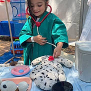 Ohana participe au concours pour gagner de l'argent avec cette photo : child, toy, stethoscope, stuffed_animal, play, doctor, green_gown, medical_table, syringe, tent, outdoor, smiling, pretend_play, young_girl, blue_mesh_hanging, plastic_container, white_container, play_kitchen, spot_pattern, happy